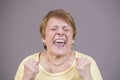 Very emotional woman screams on a gray background. Royalty Free Stock Photo