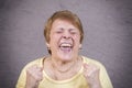 Very emotional woman screams on a gray background. Royalty Free Stock Photo