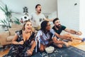 Excited friends having fun by watching football match, drinking beer and eating popcorn at home Royalty Free Stock Photo