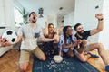 Excited friends having fun by watching football match, drinking beer and eating popcorn at home Royalty Free Stock Photo