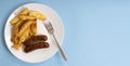 Very fatty food, fried pork sausages and potatoes on a white plate, on a blue background with copy space Royalty Free Stock Photo