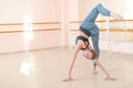 Very flexible caucasian woman doing stretching exercises in dance class with mirrors and barre.