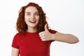 Very good, awesome. Excited ginger girl with pale skin, looking amazed at logo banner and show thumb up in approval