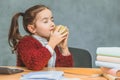 Very good schoolgirl girl sitting at the table. During this, holding a green apple in his hand holds his eyes sniffing Royalty Free Stock Photo