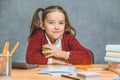 Very good schoolgirl girl sitting at the table. During this, he holds a green apple in his hand, placing a hand on his Royalty Free Stock Photo