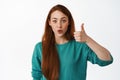 Very good. Smiling redhead woman shows her support, thumbs up and look intrigued, satisfied with idea, praise and