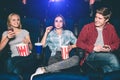Very good young friends are sitting together in cinema. Blonde gir and boy are looking at each other and smiling. She is Royalty Free Stock Photo