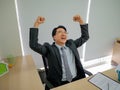 Very Happy asian business man sitting on his desk Royalty Free Stock Photo