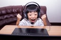 Very happy child playing game online with laptop stay at home. Asian boy student online learning class study online video call Royalty Free Stock Photo