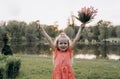Very happy little girl with her hands up and a bouquet of flowers