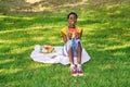 Very happy smiling black African woman sitting in an outdoor park while eating a watermelon and more fruit. Royalty Free Stock Photo