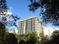 A very high modern building in Egypt surrounded with trees and green areas against a blue cloudy sky at the daylight Royalty Free Stock Photo