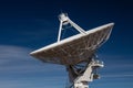 Very Large Array side view of white radio antenna satellite dish against a deep blue sky