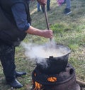 Very large cauldron cooking food during campfire, big pots on fire preparing during food festival