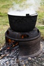 Very large cauldron cooking food during campfire, big pots on fire preparing during food festival