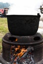 Very large cauldron cooking food during campfire, big pots on fire preparing during food festival