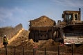 large haul dump truck at a construction site with a worker nearby as well as a bulldozer