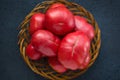 Very large ripe tomatoes in a large wicker wooden plate on a black background