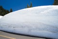 Very large snowdrift by the roadside on a blue sky day