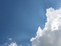 Very Large White Cumulus Fluffy cloud in the Blue Sky behind the sun beams Royalty Free Stock Photo