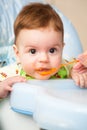 Very little kid eats fresh tasty nutritious curds on highchair Royalty Free Stock Photo