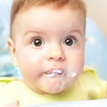 Very little kid eats fresh tasty nutritious curds on highchair Royalty Free Stock Photo