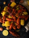 Very nice bright dish - boiled crayfish with corn. Bright colors and dark background. Black plate. View from above. High angle