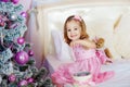 Very nice charming little girl blonde in pink dress sitting on a child`s bed and laughs loudly the background of Royalty Free Stock Photo