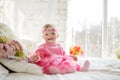 Very nice charming little girl in pink dress laughs sitting on a bed Royalty Free Stock Photo