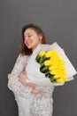 Very nice young happy woman holding big and beautiful blossoming bouquet of fresh yellow tulips flowers on the grey wall Royalty Free Stock Photo