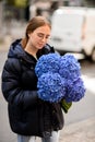 Very nice young woman holding big and beautiful bouquet of fresh hydrangea flowers in blue colors Royalty Free Stock Photo