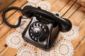 Old black phone on lace tablecloths and wooden background Royalty Free Stock Photo