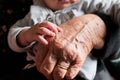 Small baby hand touching and caressing old grandmother hand with wrinkles, symbol of passing generations