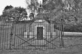 Very old mausoleum built into the side of a hill with steeple, tombstones, and wrought iron fence