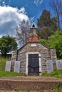 Very old mausoleum built into the side of a hill with steeple, tombstones, and wrought iron fence