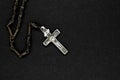 Very old metal rosary with silver cross placed on black background surface