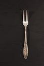Very old rusty vintage silver fork isolated on a black cement texture background