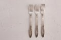 Very old set of three rusty vintage silver forks on a white cement texture background