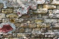 A very old stone wall with fragments of plaster, destroyed over time by weather conditions.