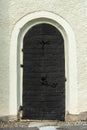 Very old vaulted black door in a white church wall Royalty Free Stock Photo