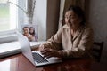 very old woman using laptop sitting at home