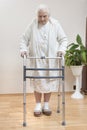 Very old woman in a white bathrobe and nightgown goes with the help of a rehabilitation balcony Royalty Free Stock Photo