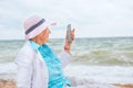 A very old wrinkled woman in a playful mood looks at her phone