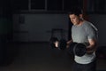 Very power athletic guy bodybuilder, execute exercise with dumbbells, in dark gym. Royalty Free Stock Photo