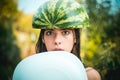 Very ridiculous girl writhes her face holding two halves of watermelon. The biggest discounts for all autumn clothes for