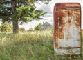 Very rusty antique old fridge sitting outside in summer. Royalty Free Stock Photo