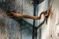 Very rusty door hook closing a wooden door, closeup. An old wooden gate locked with an equally old rusty hook . Vintage background Royalty Free Stock Photo