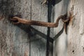 Very rusty door hook closing a wooden door, closeup. An old wooden gate locked with an equally old rusty hook . Vintage background Royalty Free Stock Photo