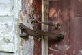 Very rusty padlock closing a wooden door, closeup. An old wooden gate locked with an equally old rusty padlock. Vintage background Royalty Free Stock Photo