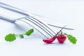 Very small cherry tomato, red chili pepper and mustard leaves on white table with fork and knife on the background Royalty Free Stock Photo